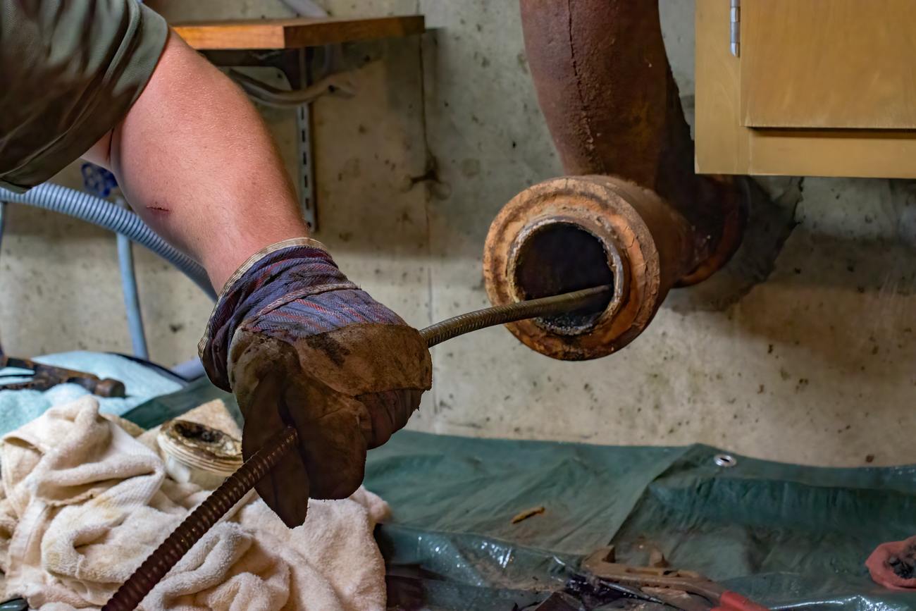 Technician running a drain cable into an old cast-iron sewer line during a drain cleaning