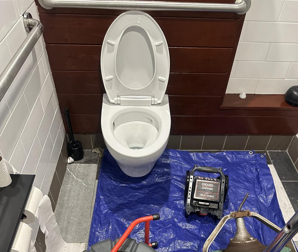 Drain cleaning equipment set up in a commercial restaurant restroom to clear a clogged toilet